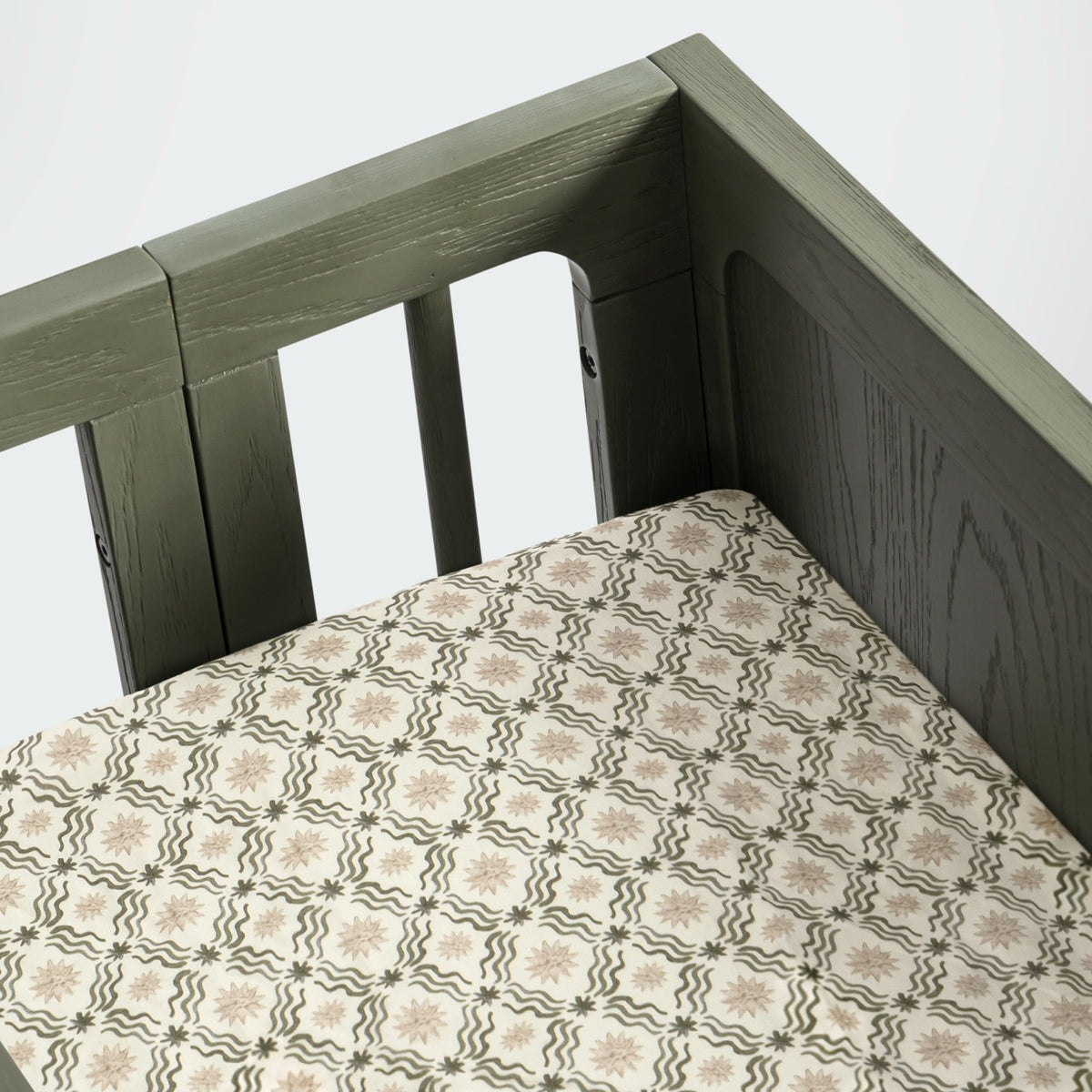 Babyletto crib with patterned sheet featuring star and wave motifs