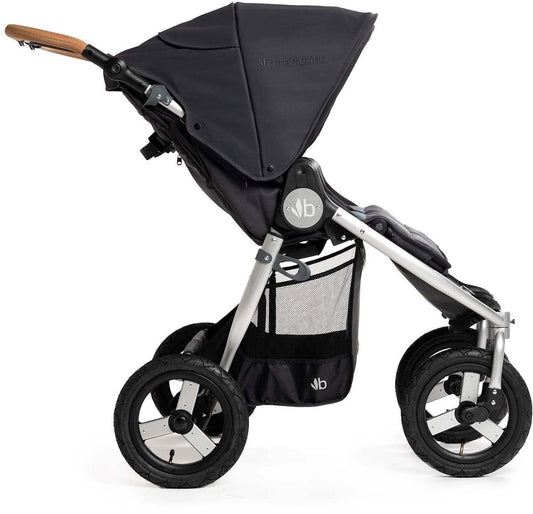 Dark gray side-by-side double stroller by Bumbleride with silver frame, wooden handle, black wheels, and mesh storage basket, front three-quarter view