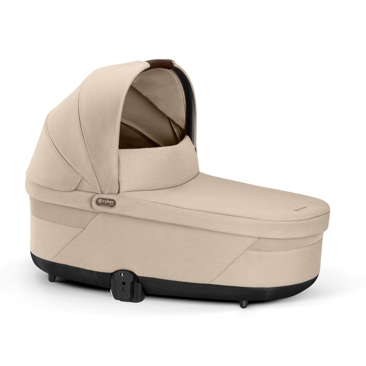 Almond beige bassinet by Cybex with soft fabric, black base, and side view angle