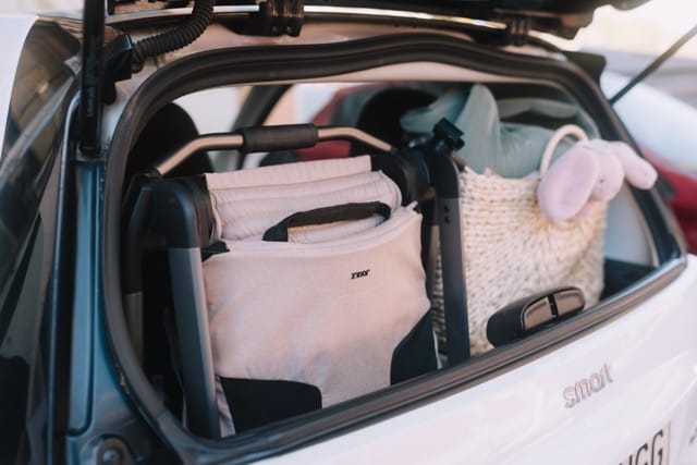 Folded Joolz stroller stored in the trunk of a white car