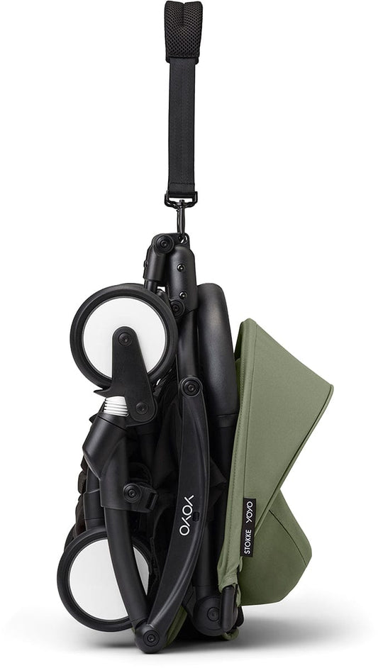 Black and olive green compact stroller by Stokke, featuring padded seat, adjustable canopy, and four wheels, side view.