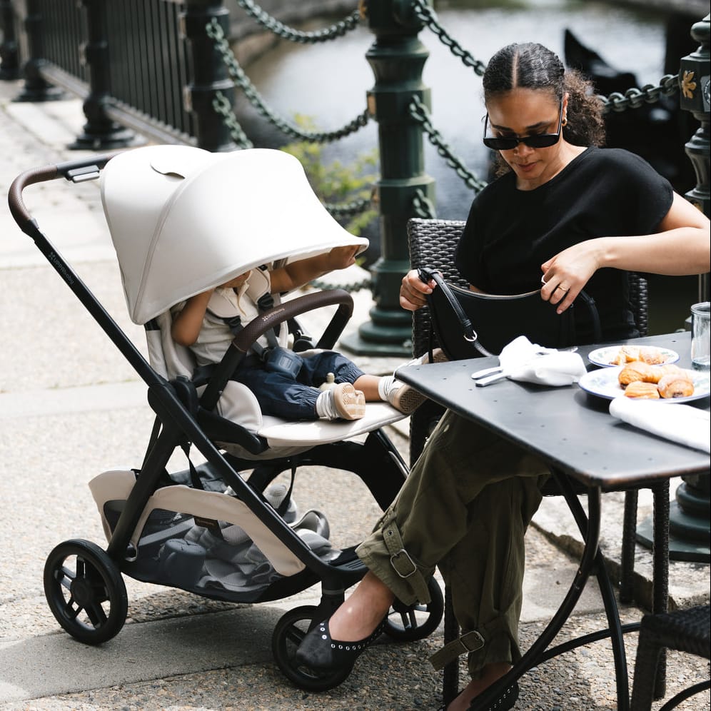 Woman sitting at an outdoor table with a child in an UPPAbaby stroller