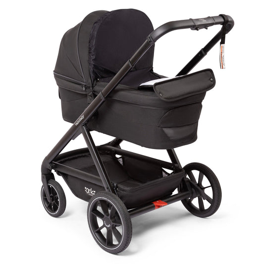 Black Valco OPEN BOX Ark bassinet by Valco Baby, side view with matte black frame, large wheels, and fabric canopy.