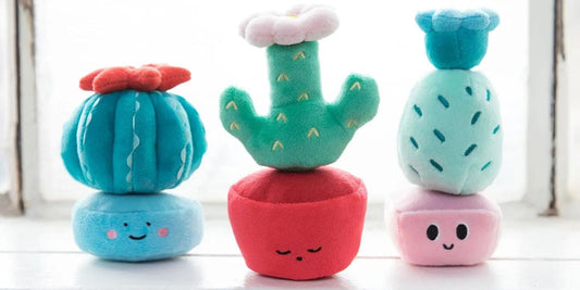 Three plush cactus stacking toys in pastel colors with smiling faces, offering a playful and educational experience for toddlers.
