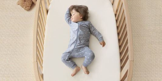 A sleeping baby in a star-patterned pajama rests peacefully in their crib, evoking a sense of calm and relaxation.

