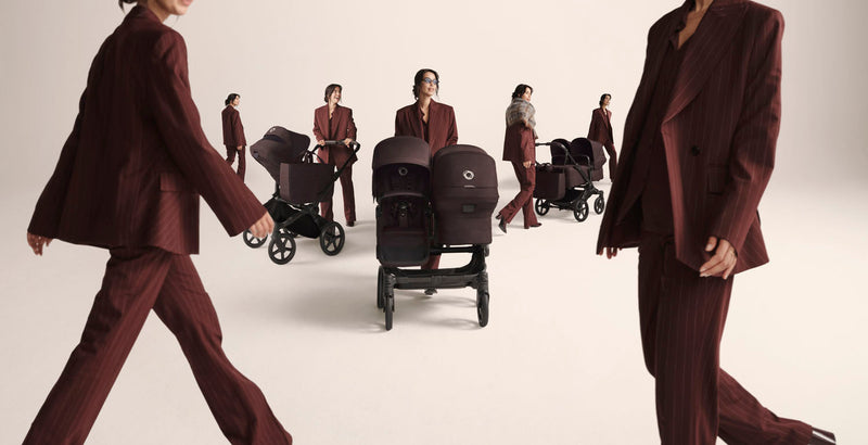 Women in burgundy suits walk confidently with Bugaboo Donkey 6 strollers in a minimalist studio setting, showcasing modern design and versatility.