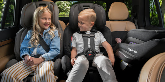 Two happy children sit safely in modern car seats in the back of a car, ready for a comfortable and secure ride. 
