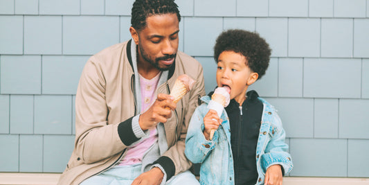 A father and son joyfully eating ice cream together, embodying a sweet and cool connection for Father's Day. 
