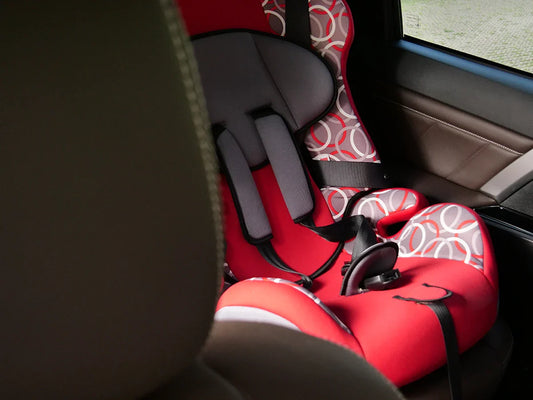 A red and gray patterned car seat sits securely in a car, ready for cleaning in this helpful guide. 
