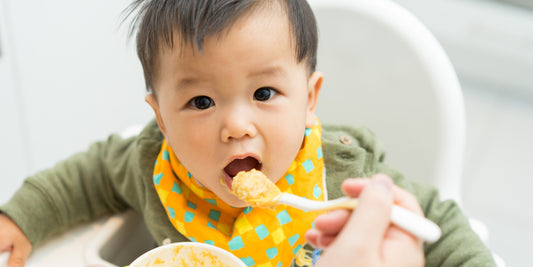 An adorable baby eagerly opens their mouth for a spoonful of food, hinting at the joys and challenges of introducing new foods.
