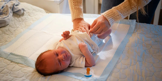 A calm, tender scene of a caregiver changing a baby's diaper, emphasizing the gentle care needed to prevent leaks.
