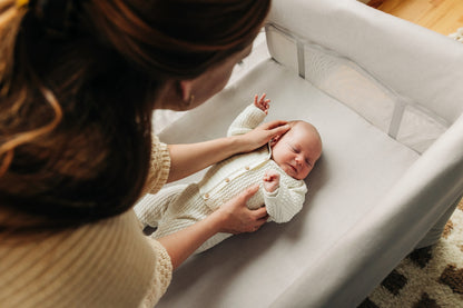 Parent placing a newborn in an UPPAbaby bassinet