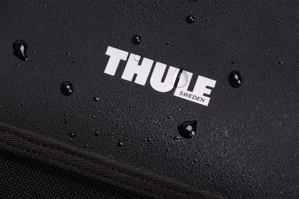 Black Thule Chasm Gear Tote 30L by Thule, water-resistant textured fabric with white logo, close-up view showing droplets on surface