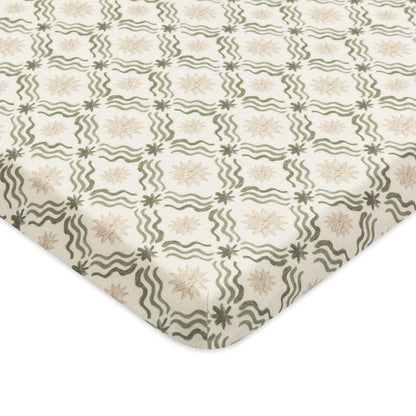 Babyletto crib sheet with a cream background featuring a repeating pattern of green wavy lines and beige starbursts