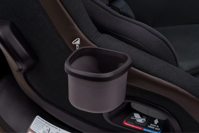 Close-up of black car seat with gray cup holder attached to side, brown trim, and safety label below.