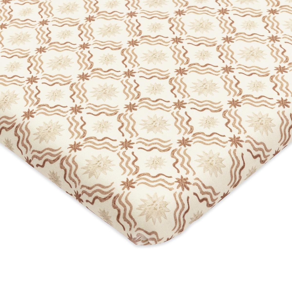 Babyletto crib sheet with a cream background and brown wavy line and star pattern