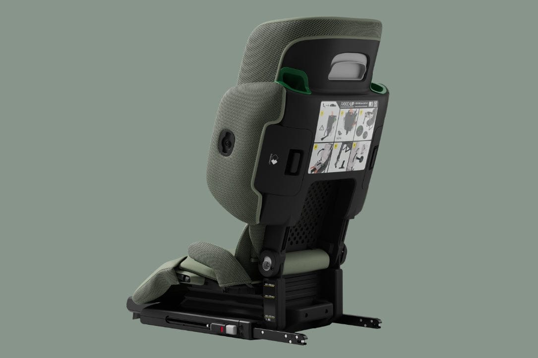 Gray and black child car seat with green accents, shown from rear with installation instructions visible on back panel.