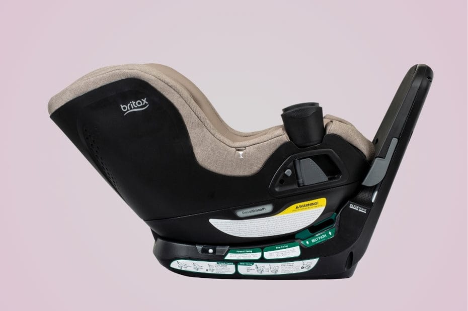 A Britax car seat features black plastic and tan fabric. Safety labels and installation instructions are visible. The background is light purple.