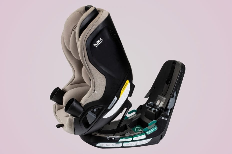 A Britax car seat in two parts, with beige fabric and black plastic, against a pink backdrop. The word "Britax" is visible on the side.