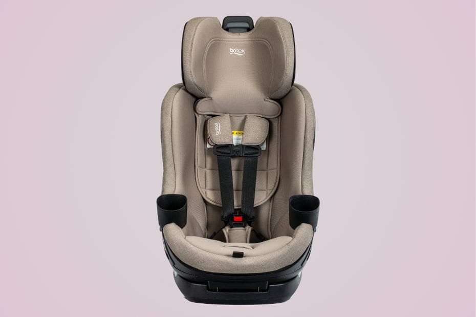 A tan Britax car seat sits centered against a light pink background. Black cup holders are on either side.