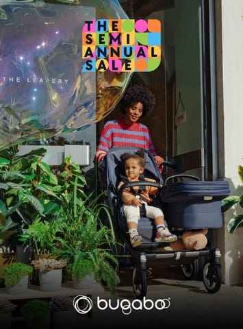Woman pushing a child in a Bugaboo stroller outside a store with a semi annual sale graphic