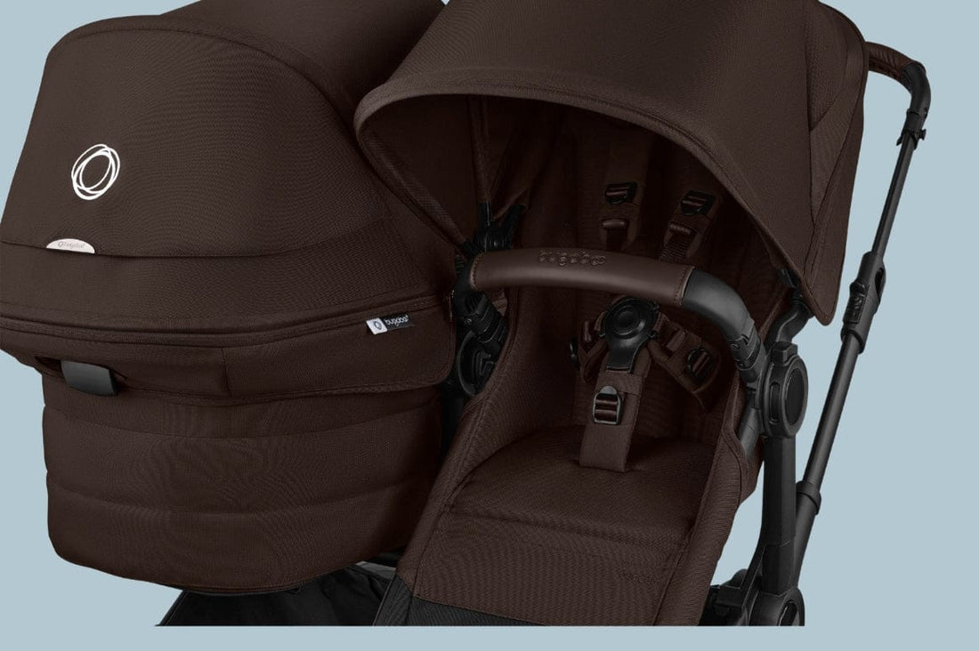 Brown baby stroller with matching carrycot, black frame, and five-point harness, displayed against light blue background.