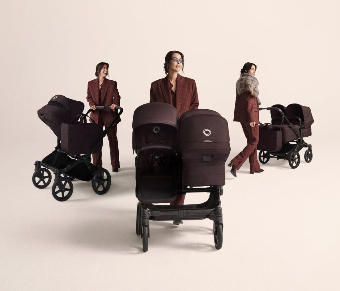 Three women in burgundy suits push matching dark purple strollers in a minimalist studio setting.