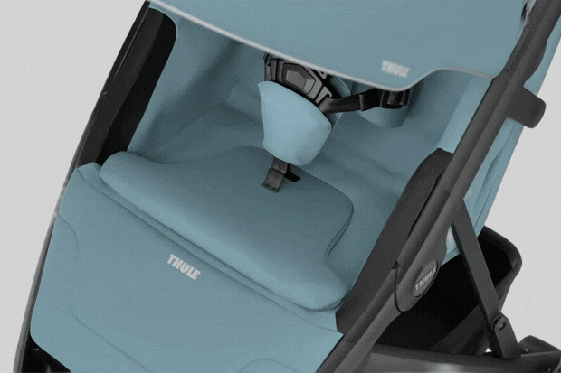 Light blue Thule child car seat with black frame, padded seat, harness, and brand logo on headrest and side.