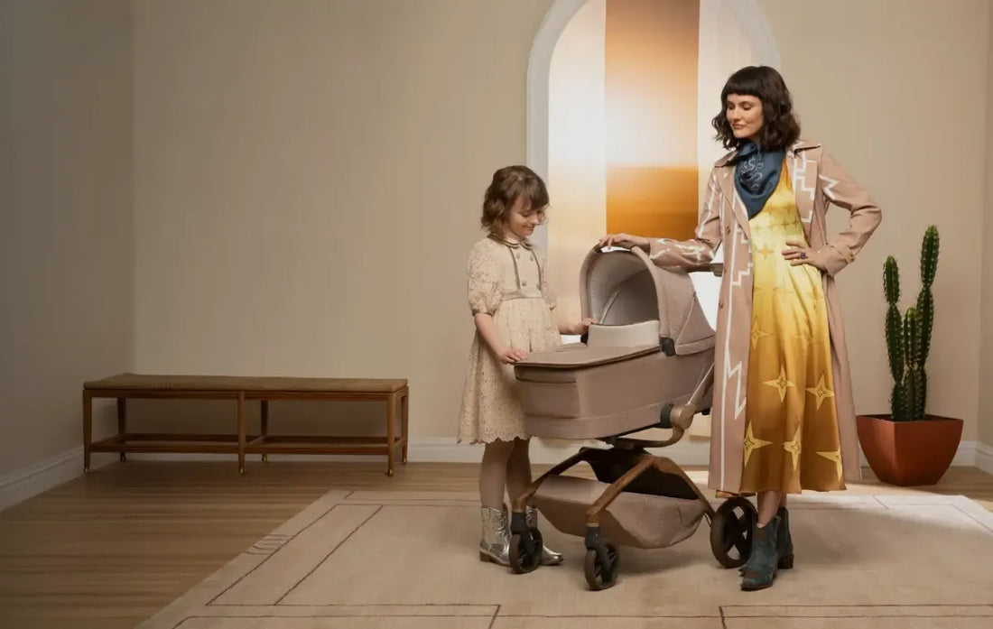 woman and child standing in a room with a maxi cosi stroller and bassinet.