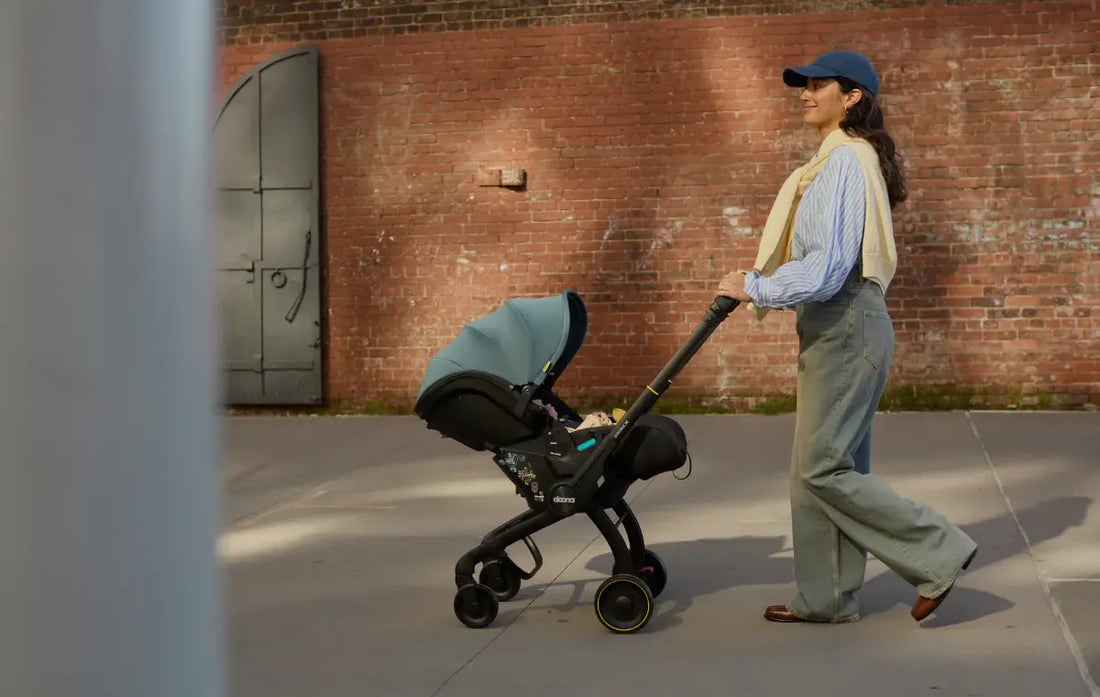 woman pushing doona x down the sidewalk with a brick building in the background.