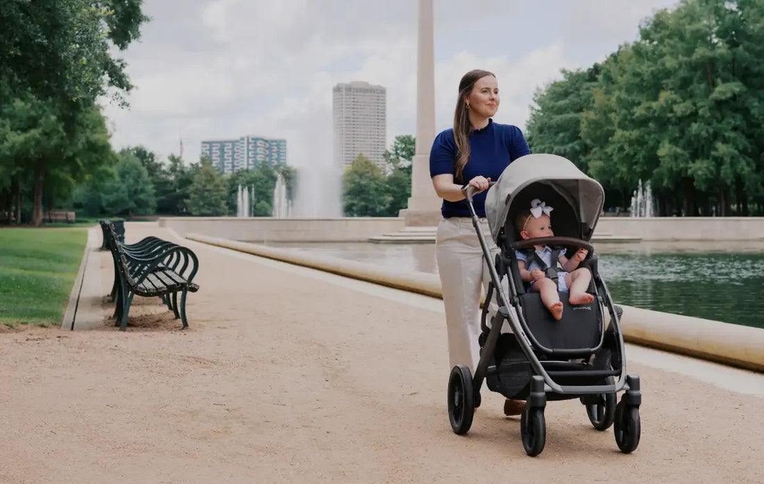 mom pushing child in the uppababy vista v3 in beau in a park.