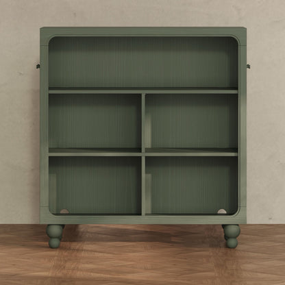 Babyletto green wooden bookshelf with four storage compartments and rounded feet