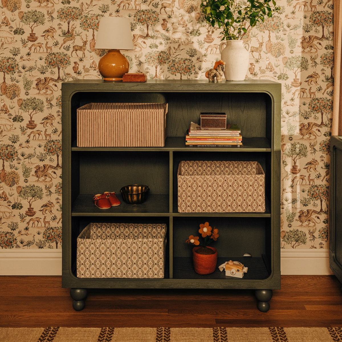 Babyletto green wooden bookcase with storage baskets and decorative items