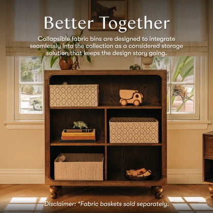 Babyletto wooden bookshelf with patterned fabric storage bins and toys on shelves