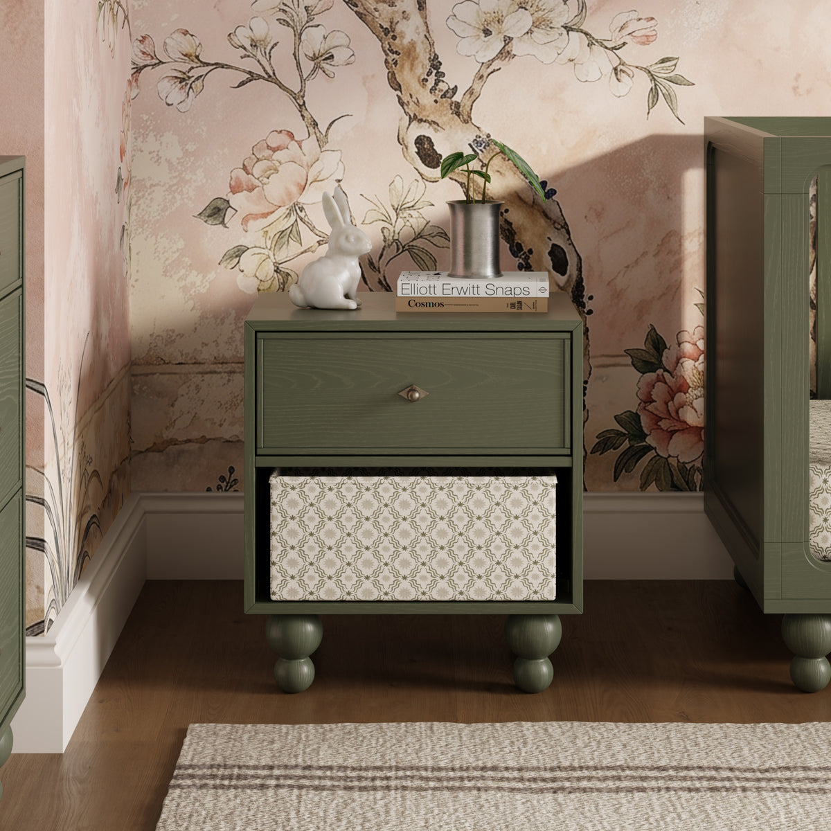 Babyletto olive green nightstand with one drawer and open storage shelf containing a patterned bin