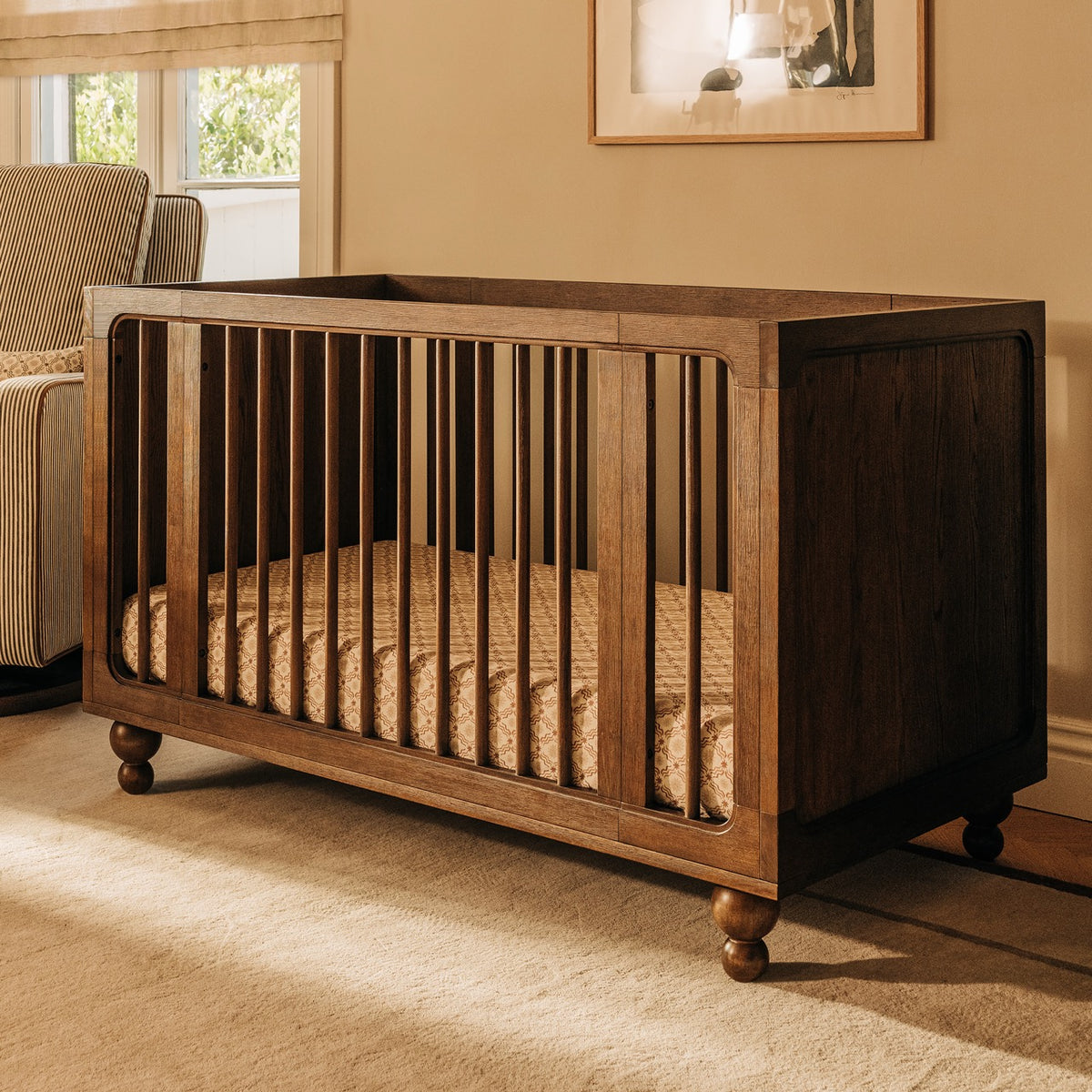 Babyletto dark wood crib with spindle sides and bun feet in a nursery
