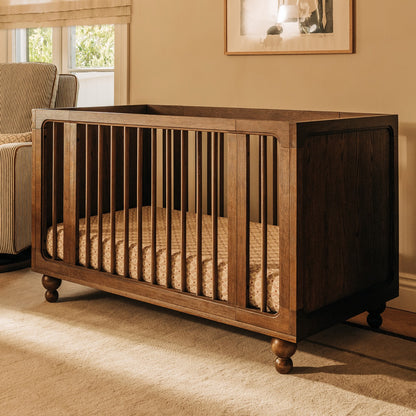 Babyletto dark wood crib with spindle sides and bun feet in a nursery