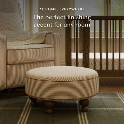 Babyletto round striped ottoman in a nursery with a matching armchair and wooden crib