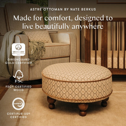 Babyletto Astre ottoman with patterned fabric and wooden feet in a nursery setting