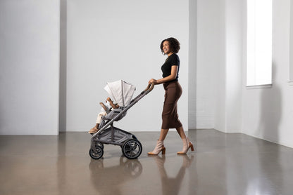 Woman pushing a Nuna stroller with a child inside