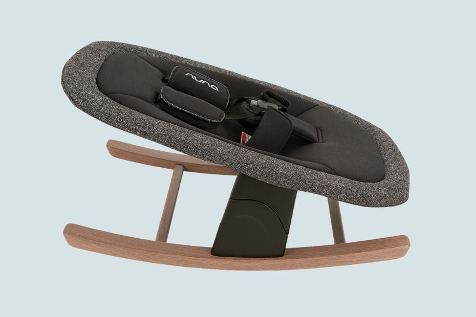 Gray fabric baby rocker with wooden base, black cushion, and "NUNA" logo on headrest, set against light background.