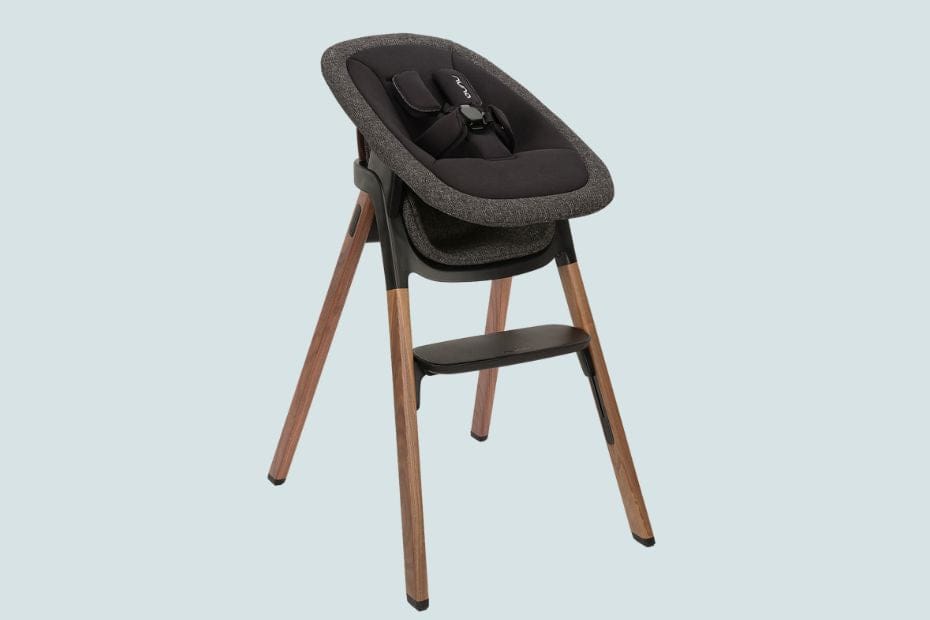 Modern high chair with dark gray fabric seat, wooden legs, and black tray on light blue background.