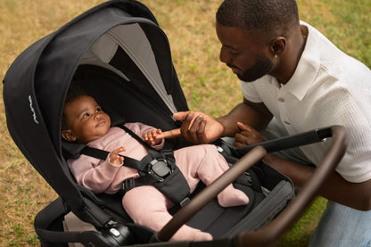 Father interacting with baby in a black Nuna stroller