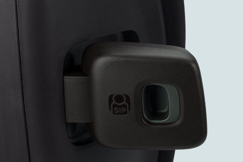 A dark-colored car seat has a side impact protection (SIP) feature extending outwards, with a recessed area. The background is light gray.