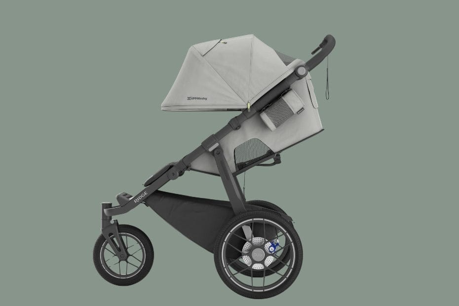 Light gray stroller with black frame and large wheels, featuring canopy, mesh storage, and "Rouge" branding on frame.