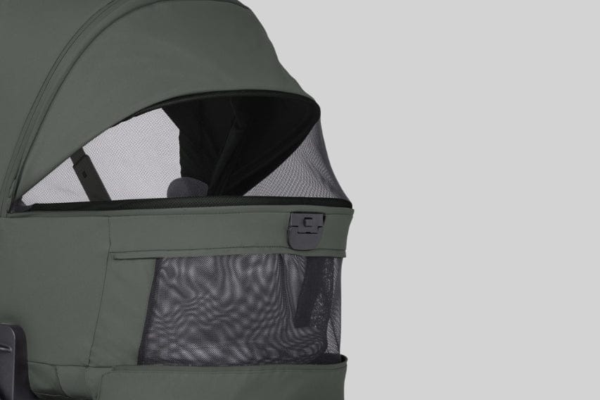 Close-up of an olive-green stroller canopy with a mesh window and pocket against a light gray background.