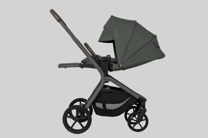 A dark gray stroller with a green canopy sits on a gray background, positioned in the center. The stroller has black wheels and a storage basket below the seat.
