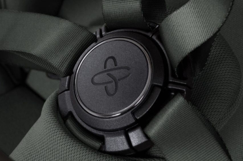Close-up of a black strap distributor with an abstract symbol on a dark green harness. Soft lighting with a muted, modern feel.
