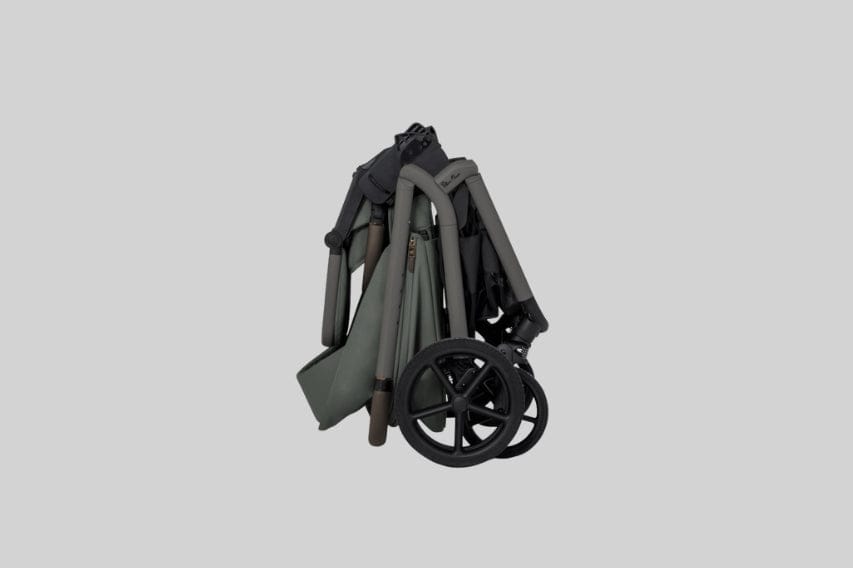 A folded stroller in muted green and black stands on a light gray surface, wheels near the bottom.
