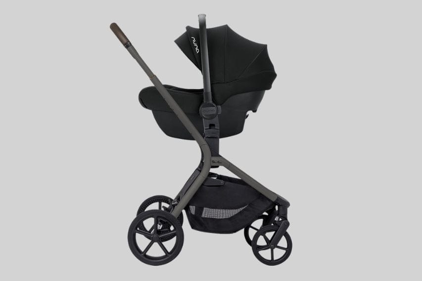 A black Nuna brand stroller with a car seat attachment is shown on a gray background.